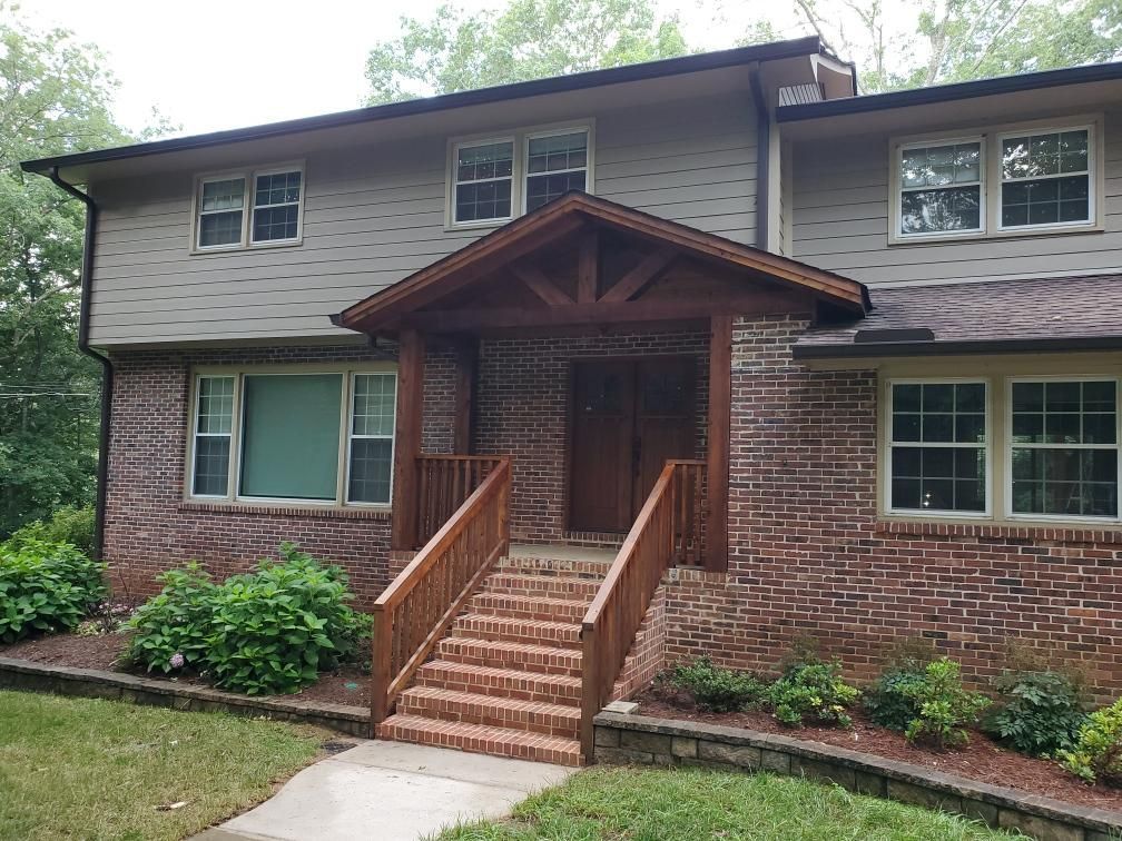 A large brick house with a wooden porch and stairs