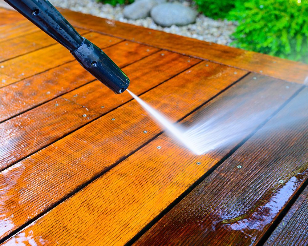 Worker Using Pressure Washer on a Deck