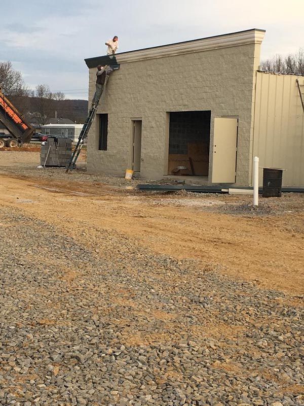 Worker with Ladder Painting Concrete Gutter