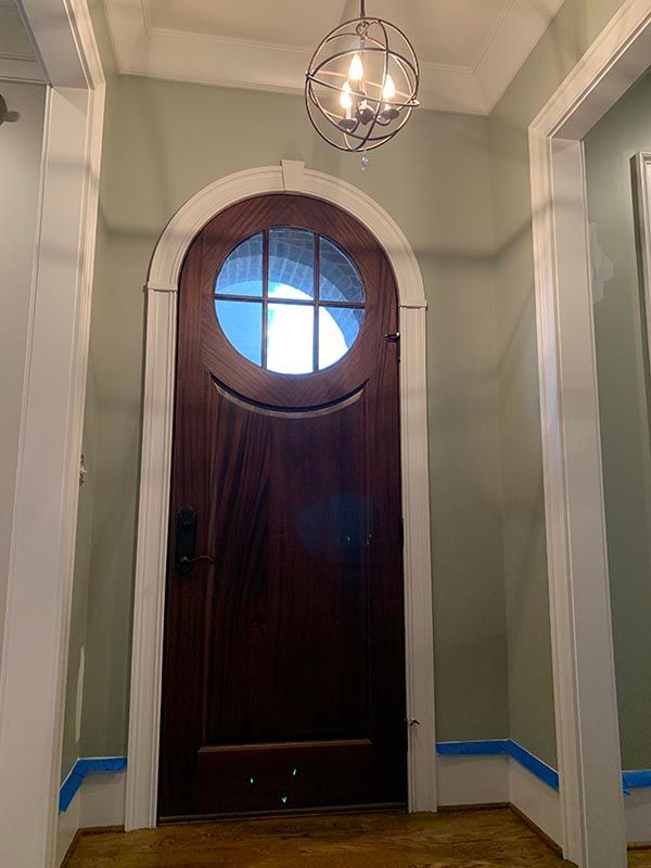 Hallway with a Wooden Door and Round Window on Top of it