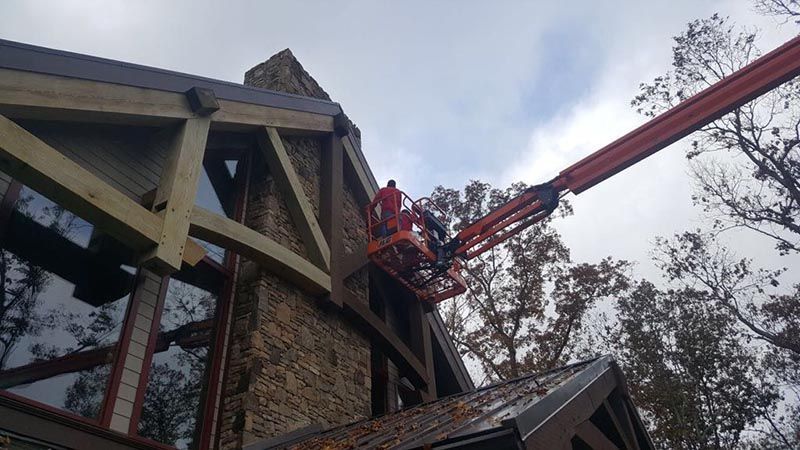 Worker on Lift Bucket Painting the Exterior of a House