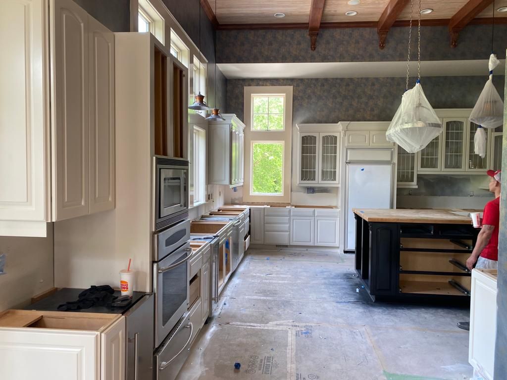 A kitchen under construction with white cabinets and stainless steel appliances