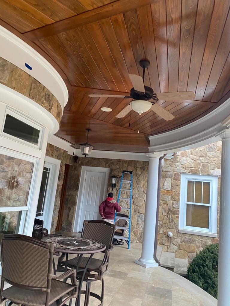 A ceiling fan is hanging from the ceiling of a porch.