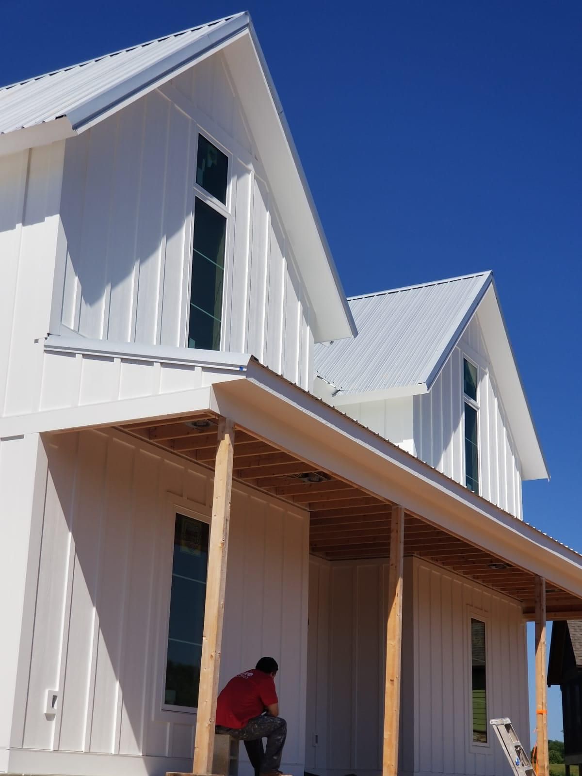 A man sits on a porch of a white house