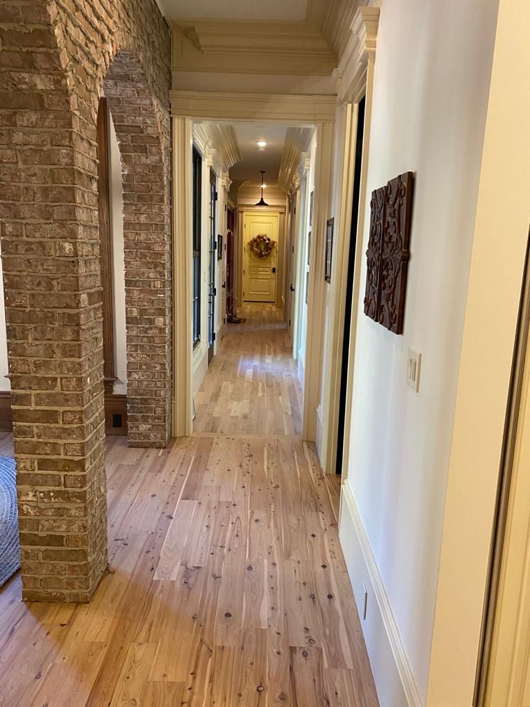 A long hallway with wooden floors and brick walls in a house.