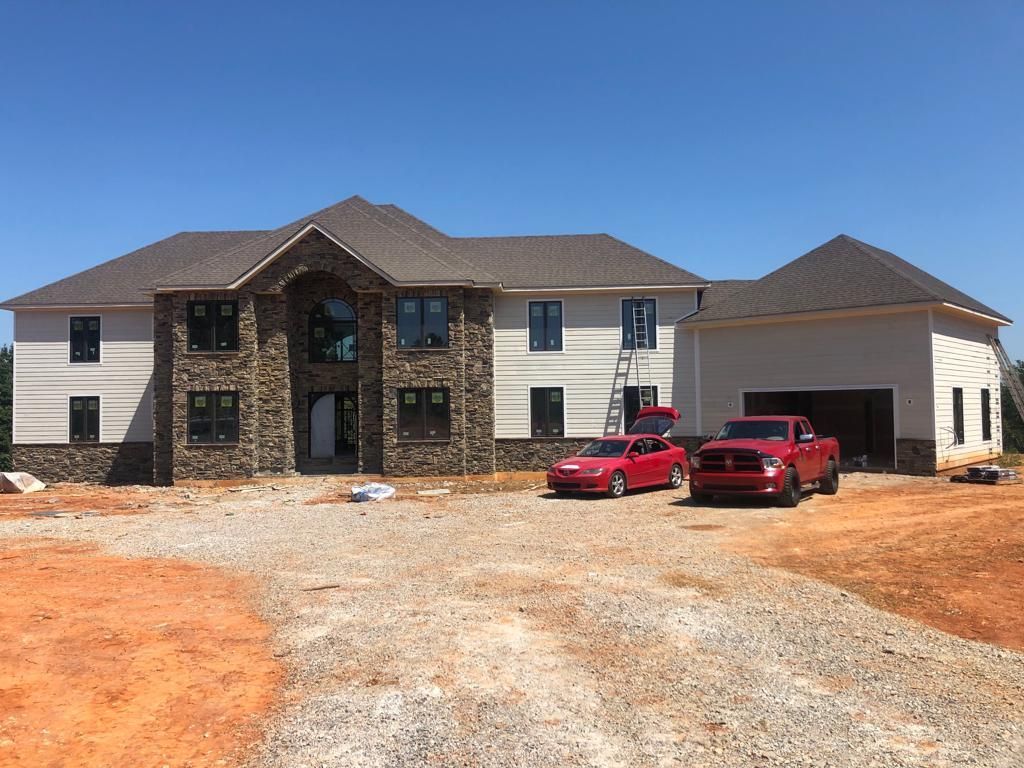 Two red trucks are parked in front of a large house under construction.