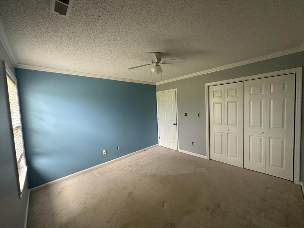 An empty bedroom with blue walls and a ceiling fan.
