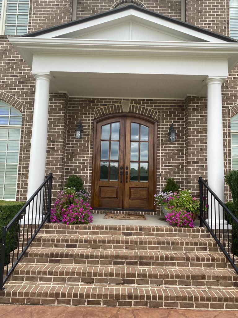 A brick house with a porch and stairs leading to the front door.