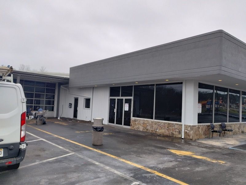 A white van is parked in front of a large building.