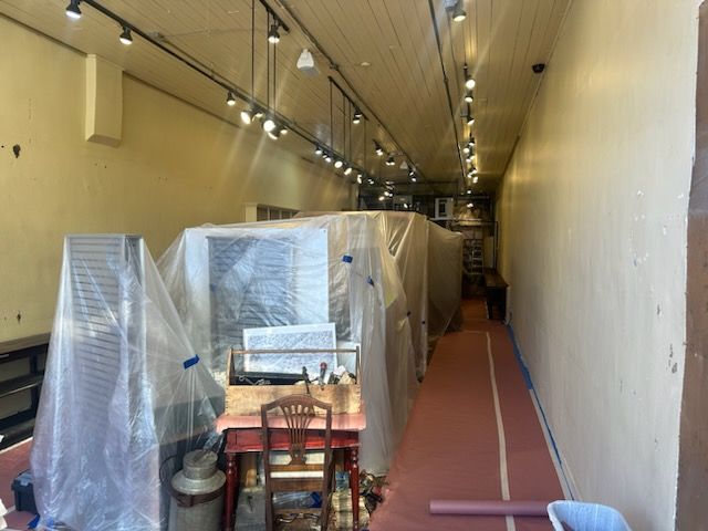 A long hallway with a table and chairs covered in plastic.