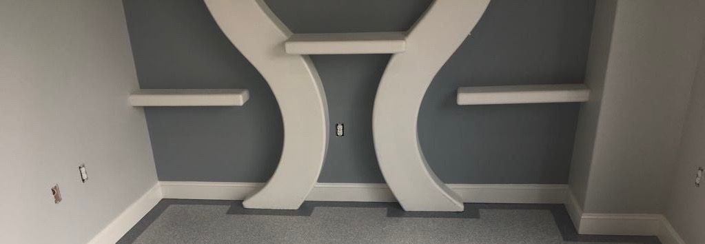 A corner of a room with a shelf on the wall.