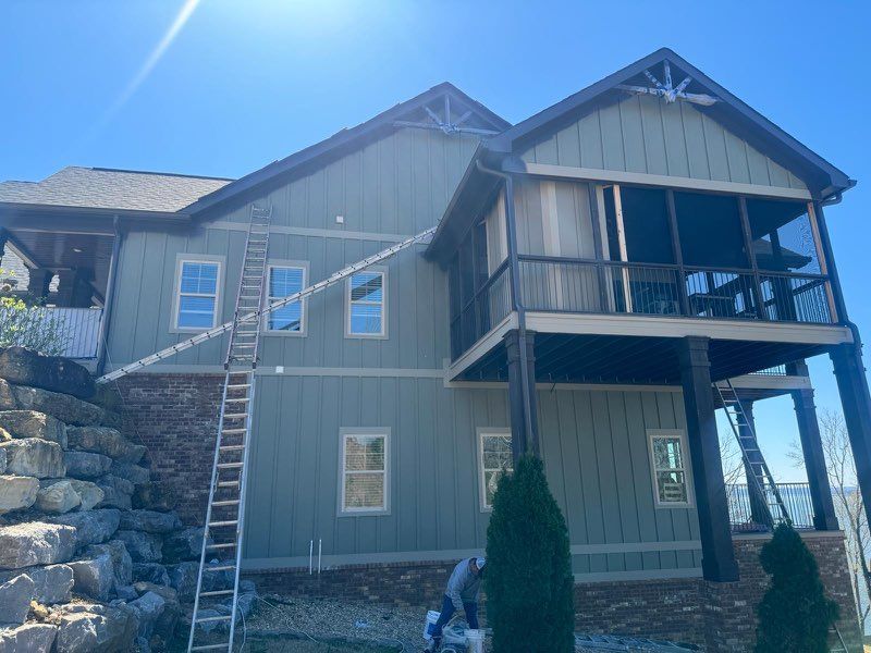 A large house with a ladder on the side of it is being painted.