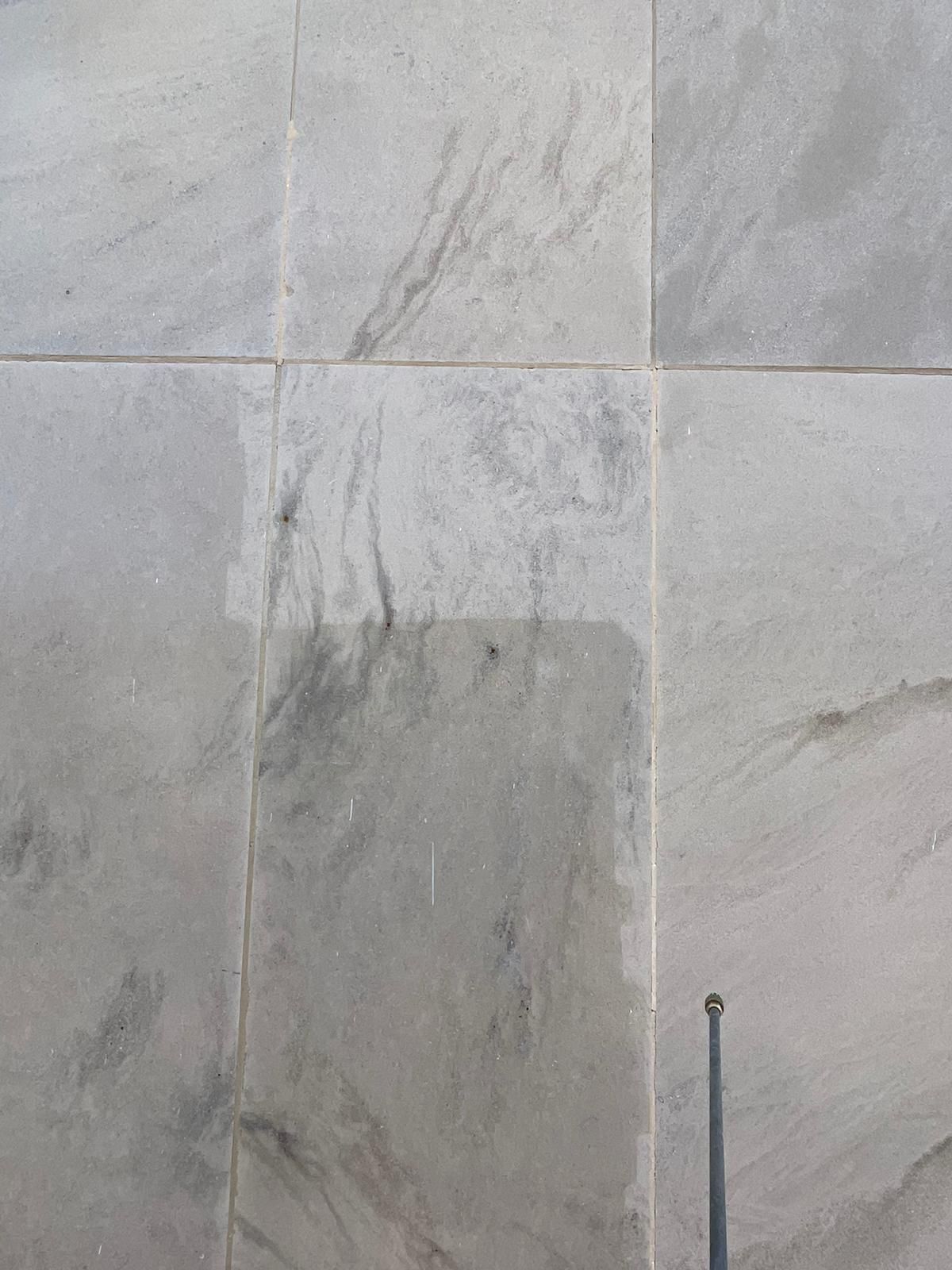 A close up of a tiled wall with a metal pole in the middle.