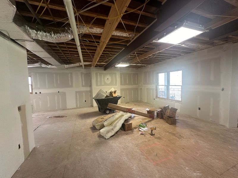 A large empty room with a dumpster in the middle of it.