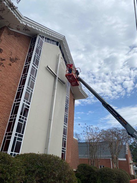 A crane is lifting a cross on the side of a church.