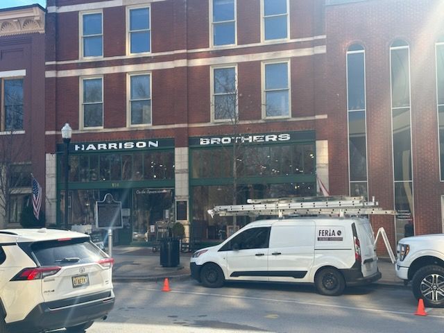 A white van is parked in front of a brick building.