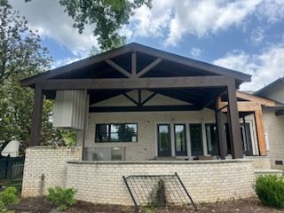 The back of a house with a covered porch and a brick wall.