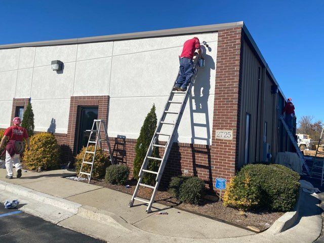 Two men on ladders are working on the side of a building.