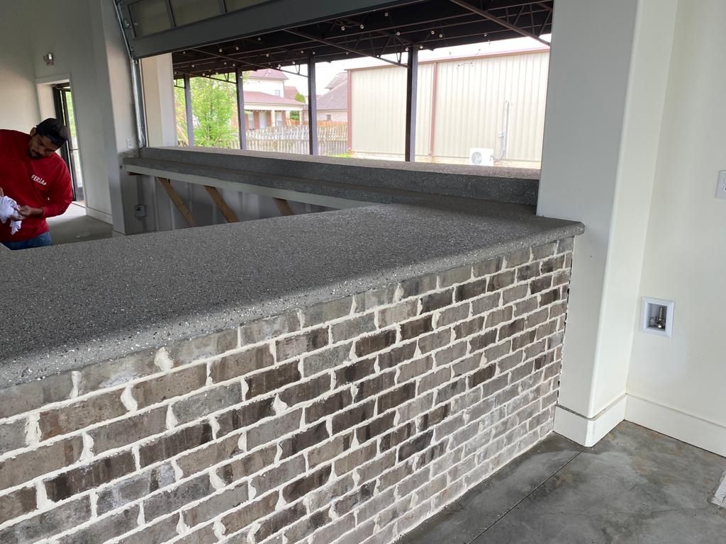 A man in a red shirt is standing in front of a brick wall.