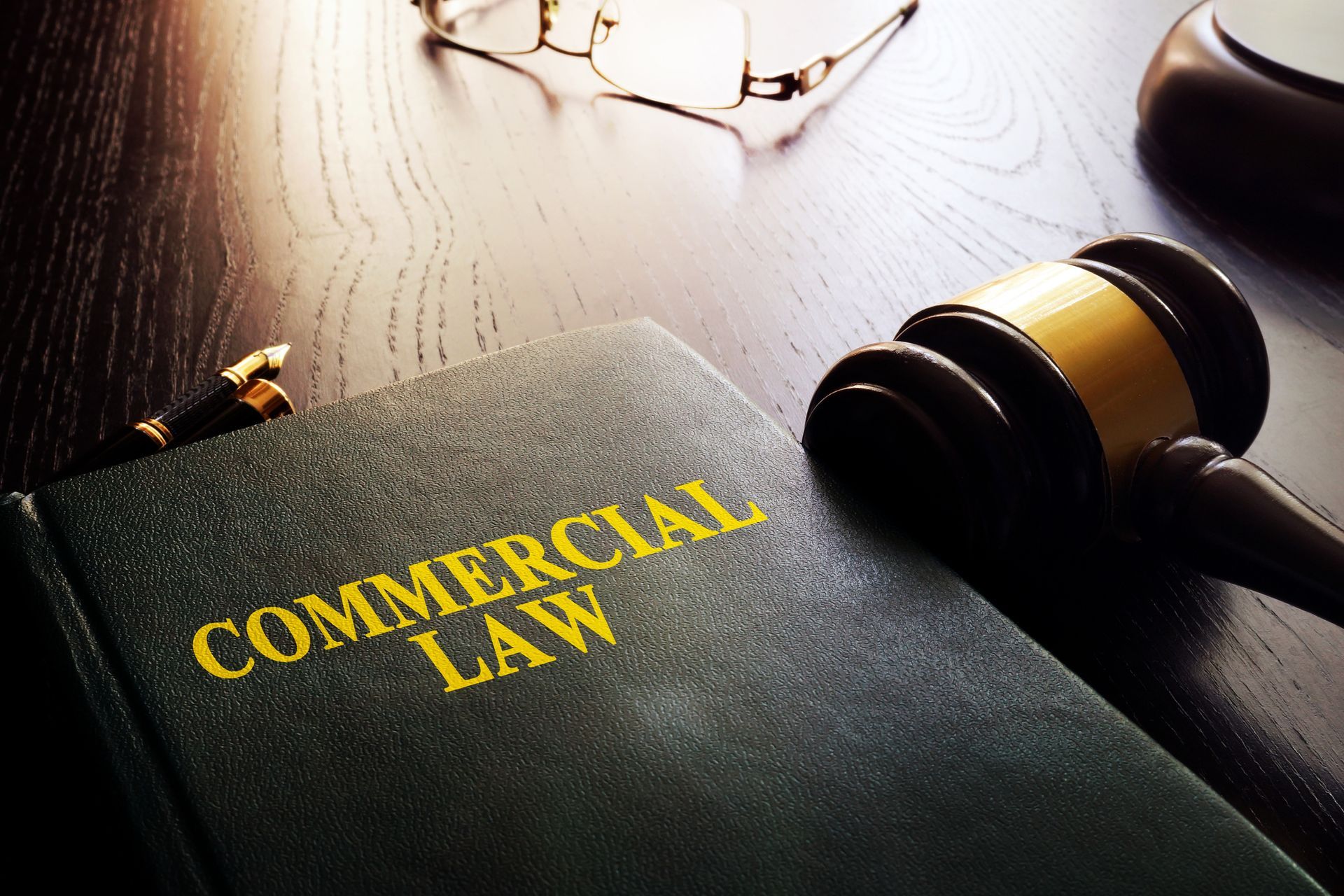 A book titled commercial law is on a wooden table next to a judge 's gavel.