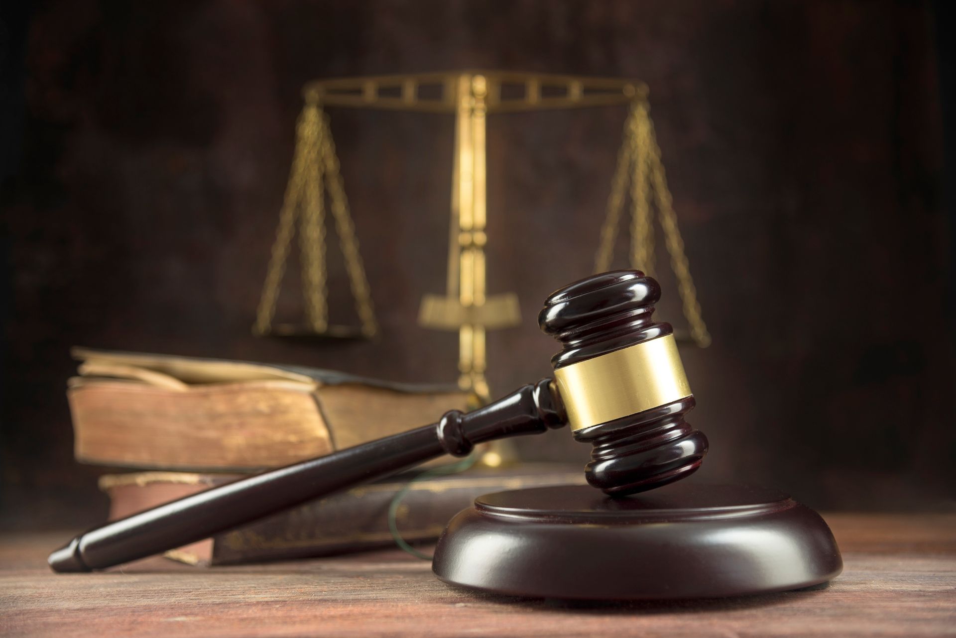 A judge 's gavel is sitting on a wooden table in front of a scale of justice.