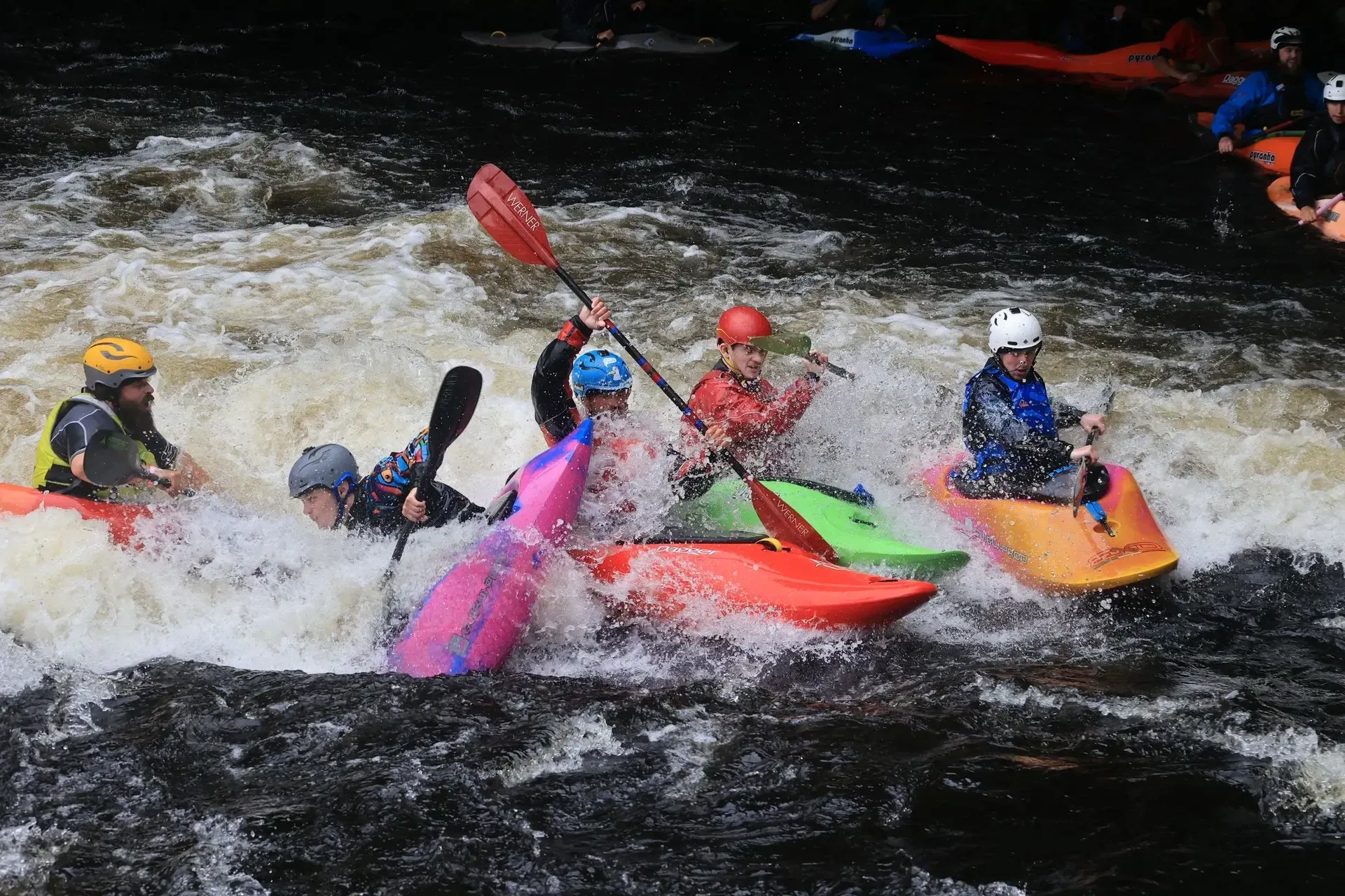 A group of people are riding kayaks down a river.