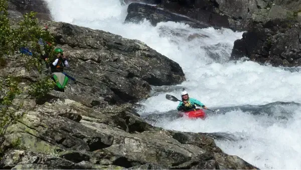 Mae dyn mewn caiac yn mynd i lawr rhaeadr.