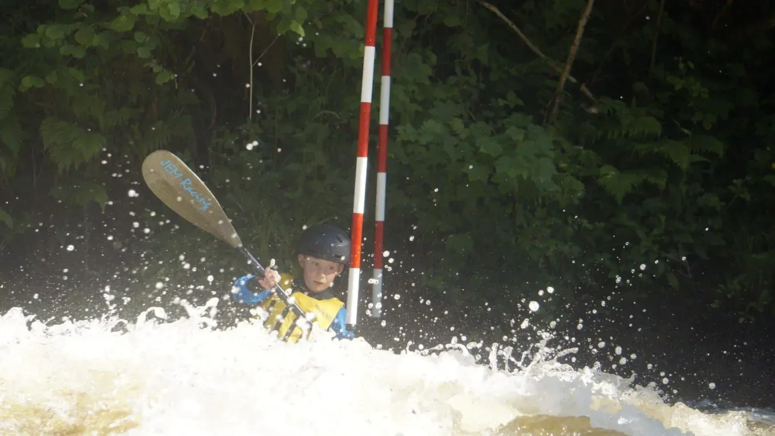 A person is paddling a kayak down a river.