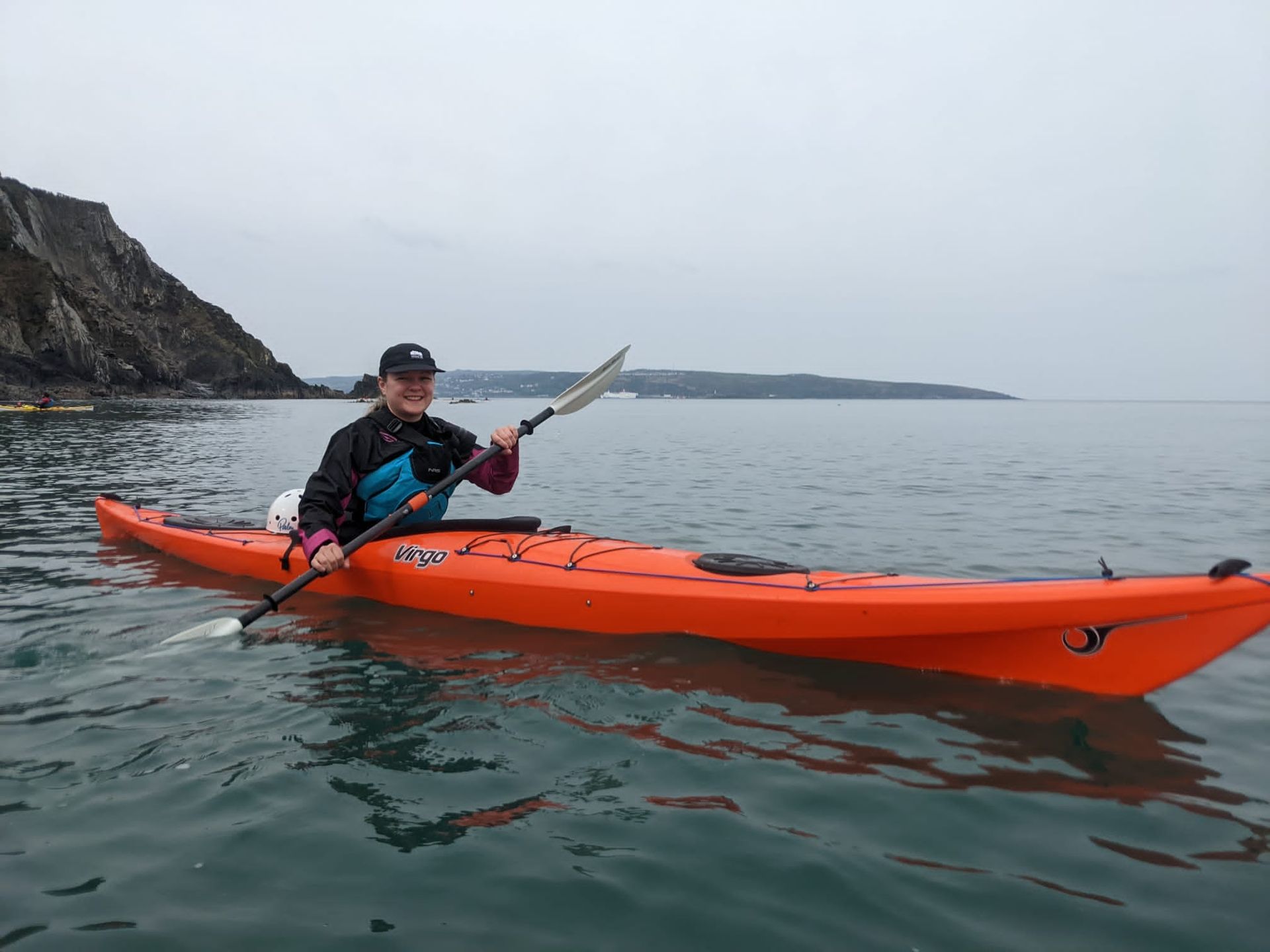 A woman is paddling a red kayak in the ocean.