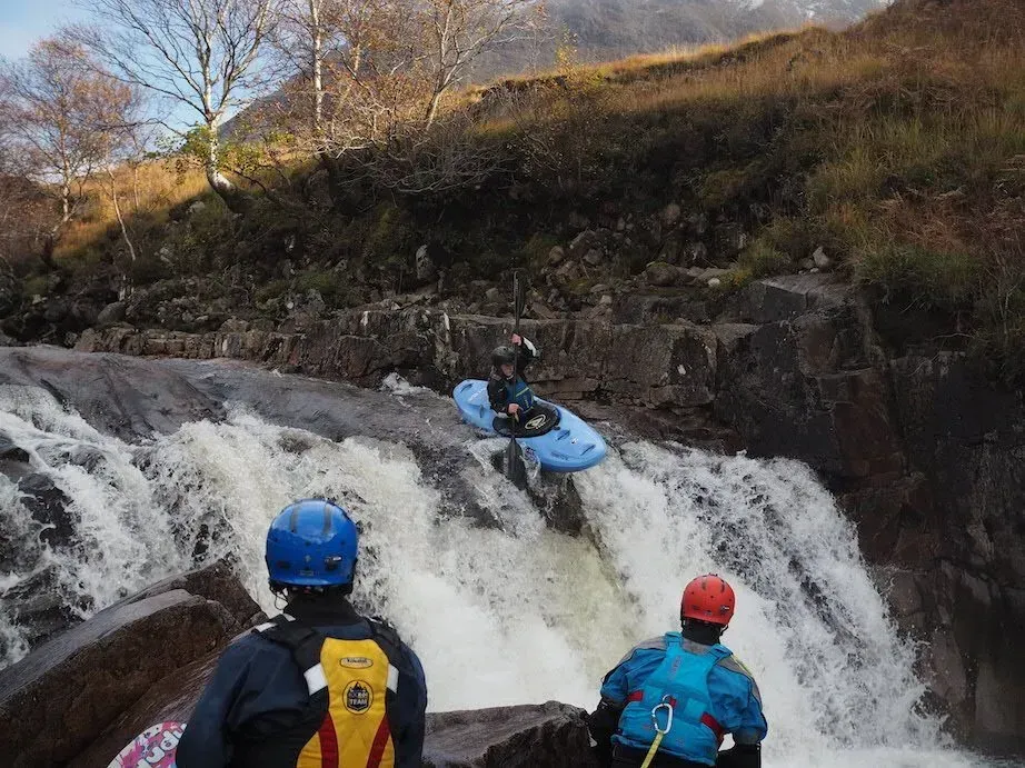 Mae dyn mewn caiac yn mynd i lawr rhaeadr.