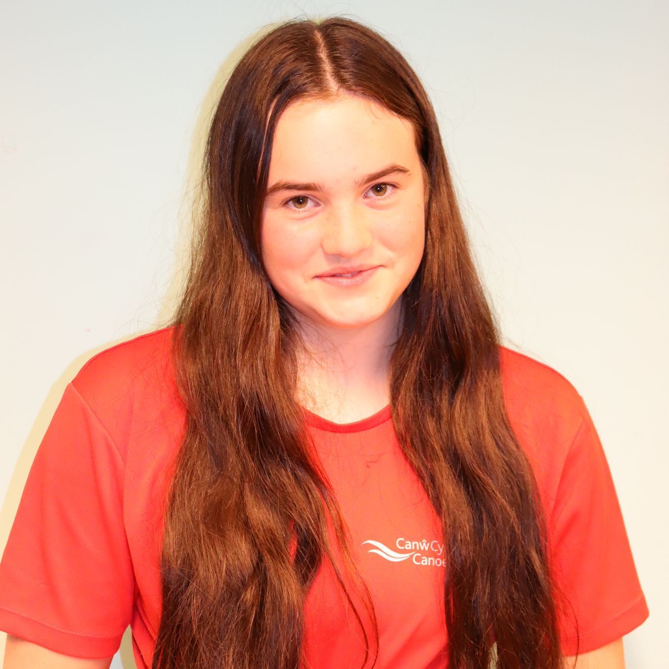 A woman with long hair wearing a red shirt that says care canada