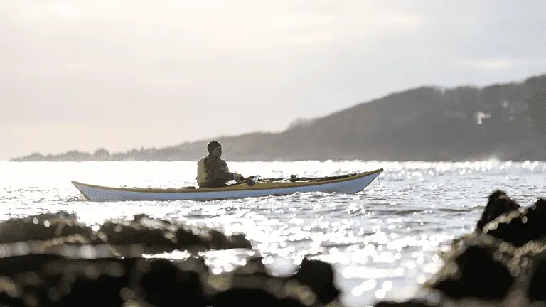 A man is sitting in a kayak in the ocean.