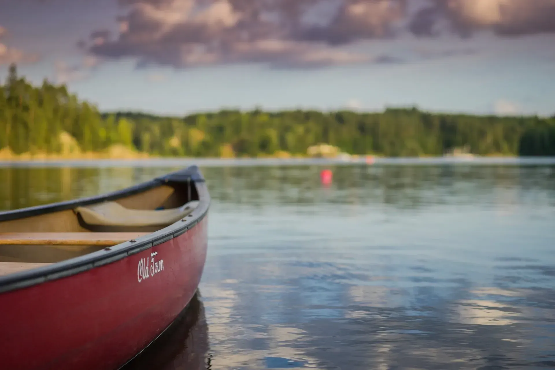 A red canoe is floating on top of a lake.