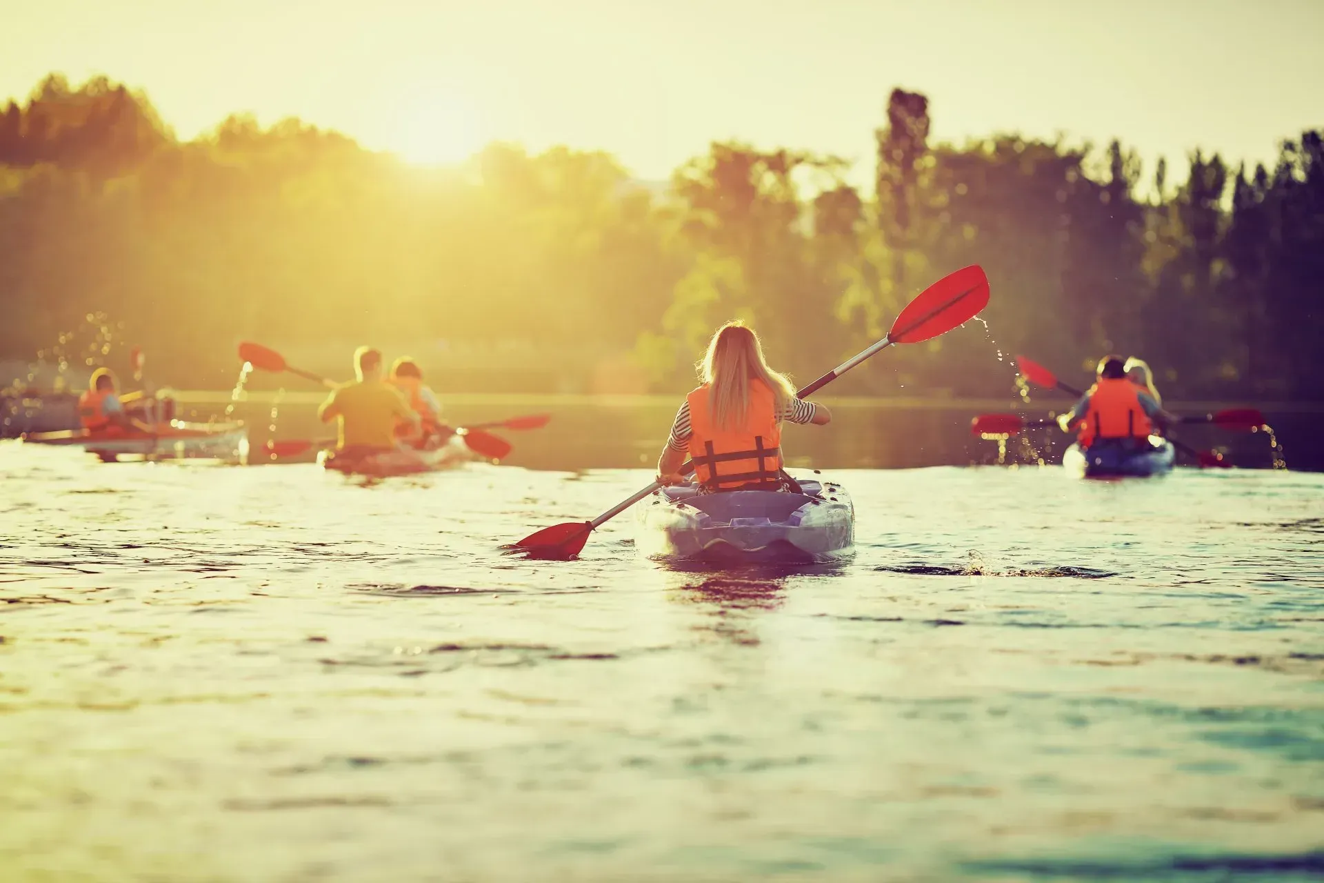 A group of people are paddling kayaks on a lake.