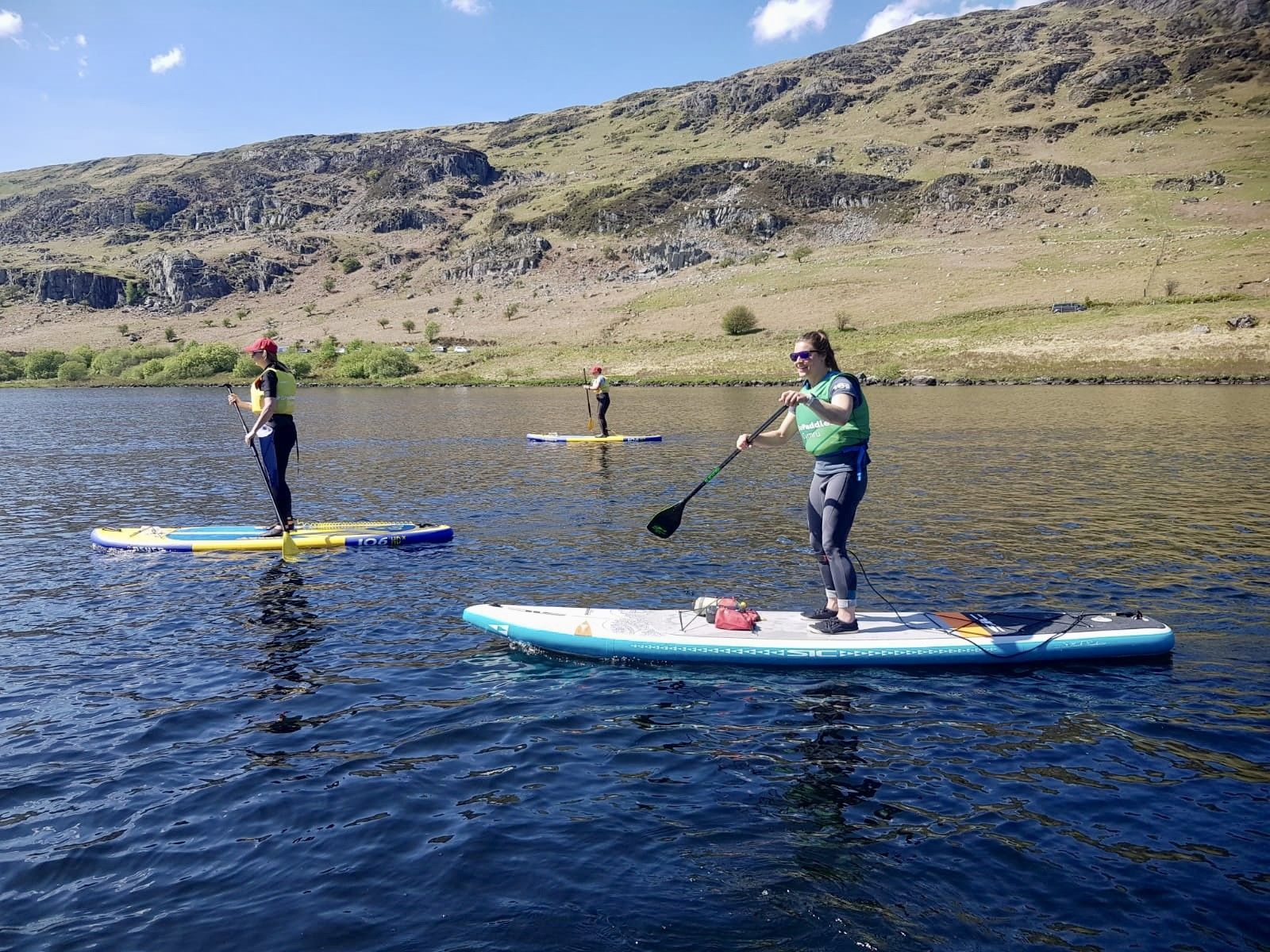 A woman is standing on a paddle board in the water.