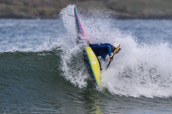 Mae person yn marchogaeth ton ar fwrdd syrffio yn y cefnfor.