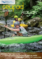 A man in a green kayak is paddling down a river.