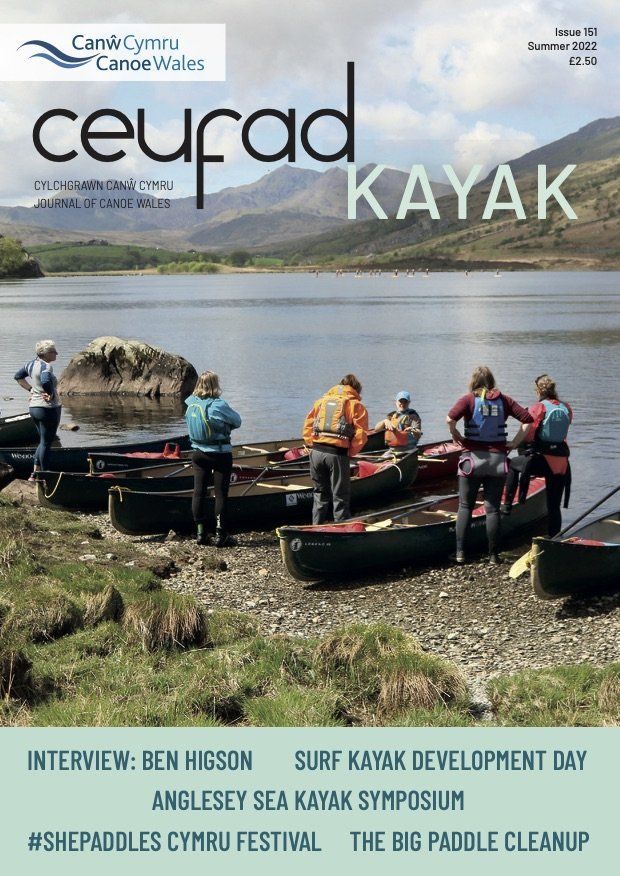 A group of people are standing in kayaks on the shore of a lake.
