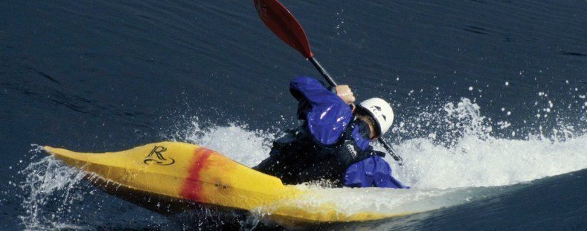 Person mewn caiac melyn gyda rhwyf coch