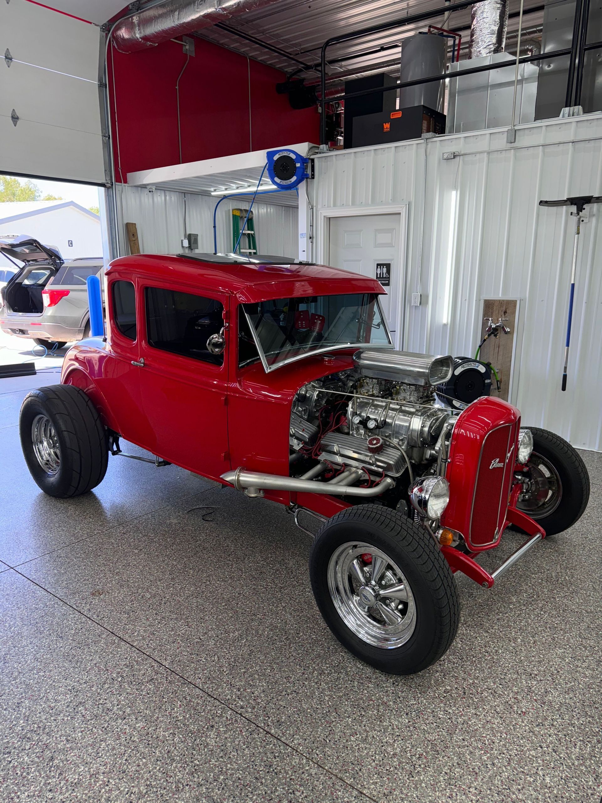 A person wearing black gloves is polishing a black car