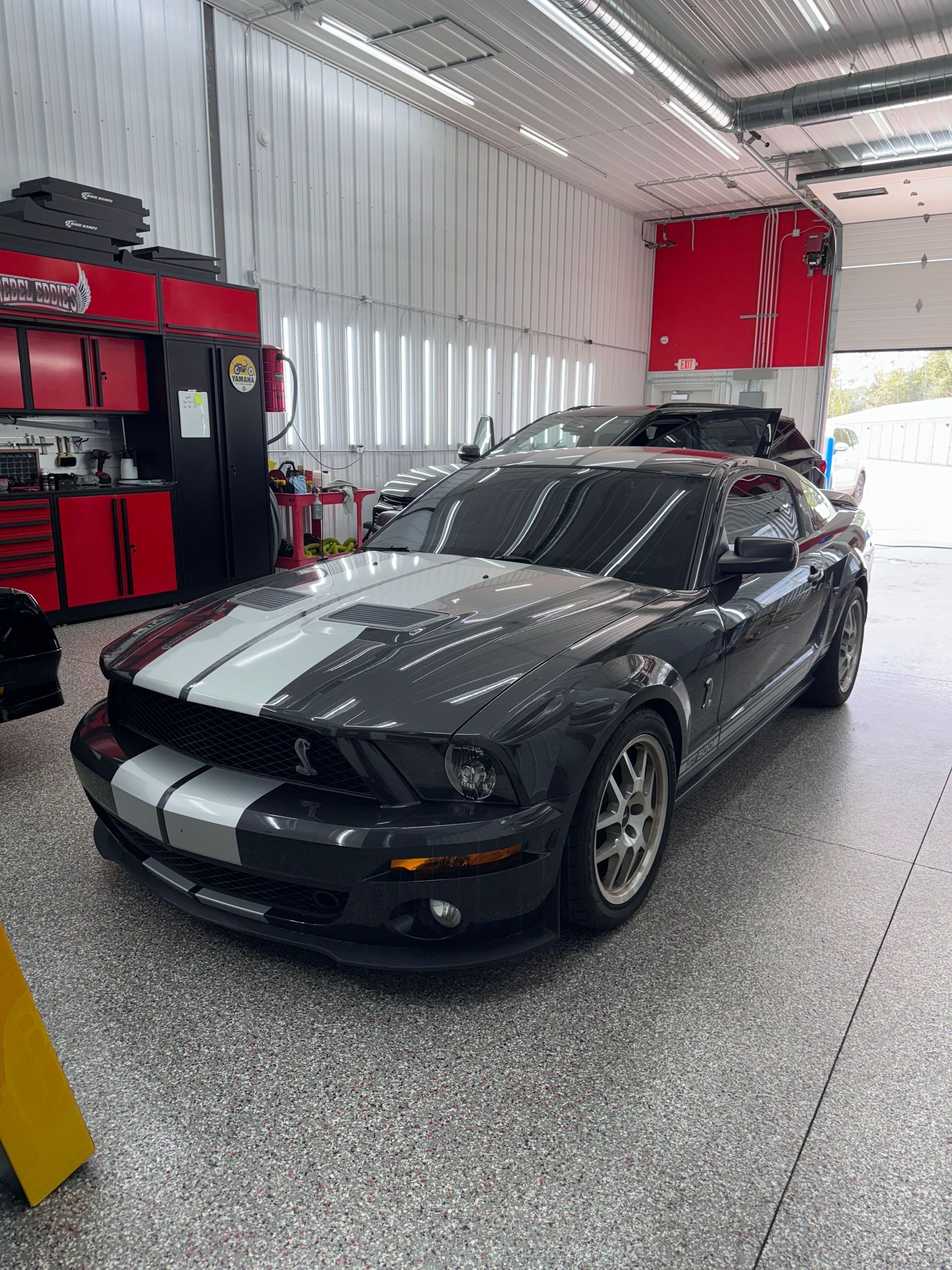 A person is cleaning a blue car with an orange towel