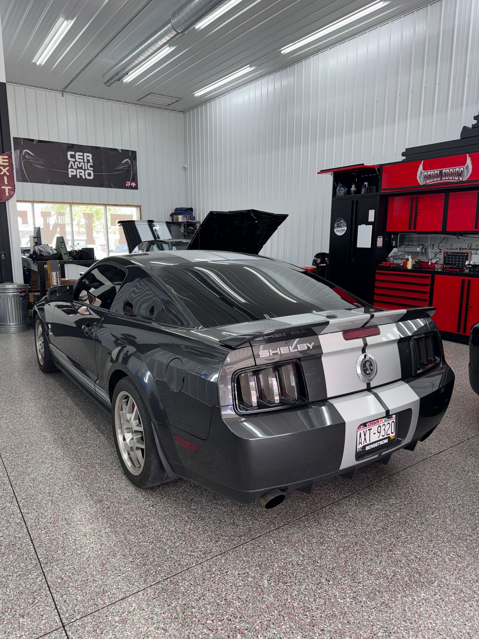 A person is cleaning a blue car with an orange towel