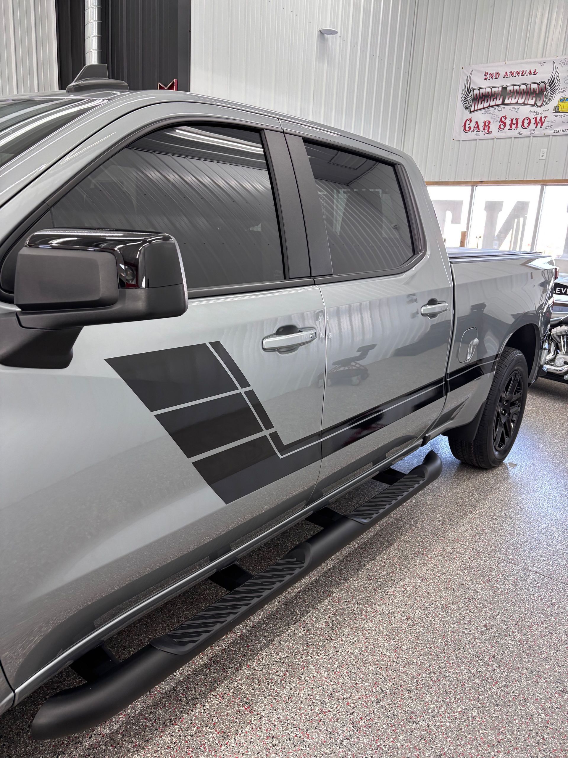 A person wearing black gloves is polishing a black car
