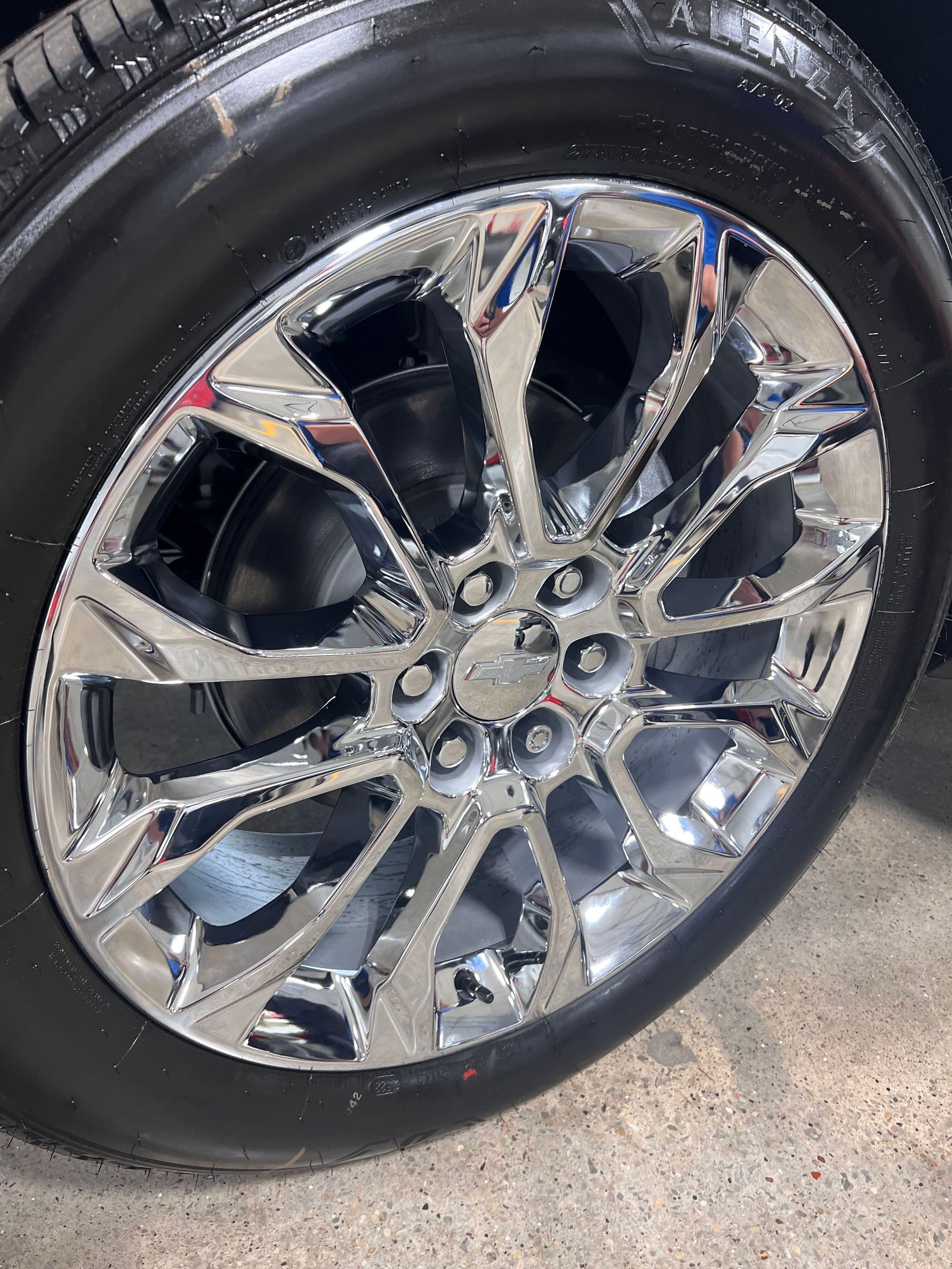 A person wearing black gloves is polishing a black car