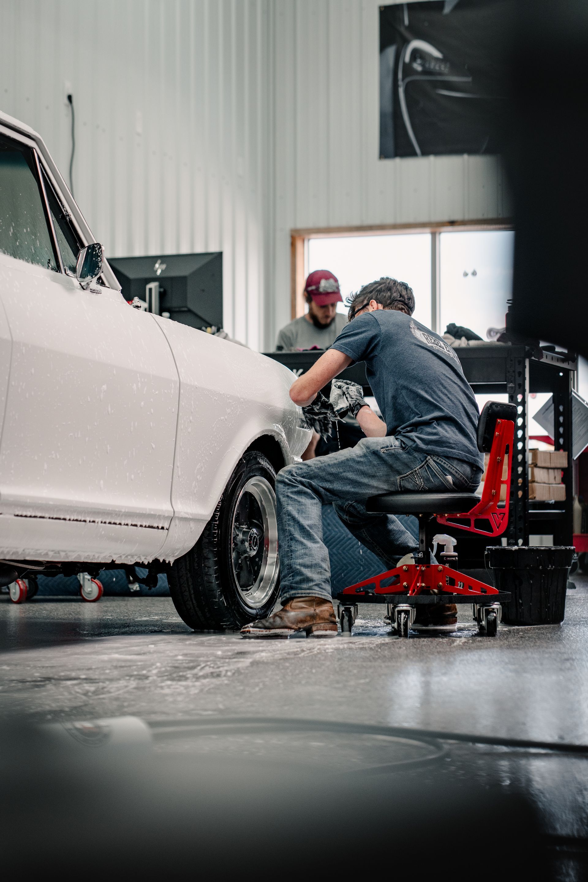 A person is cleaning a blue car with an orange towel