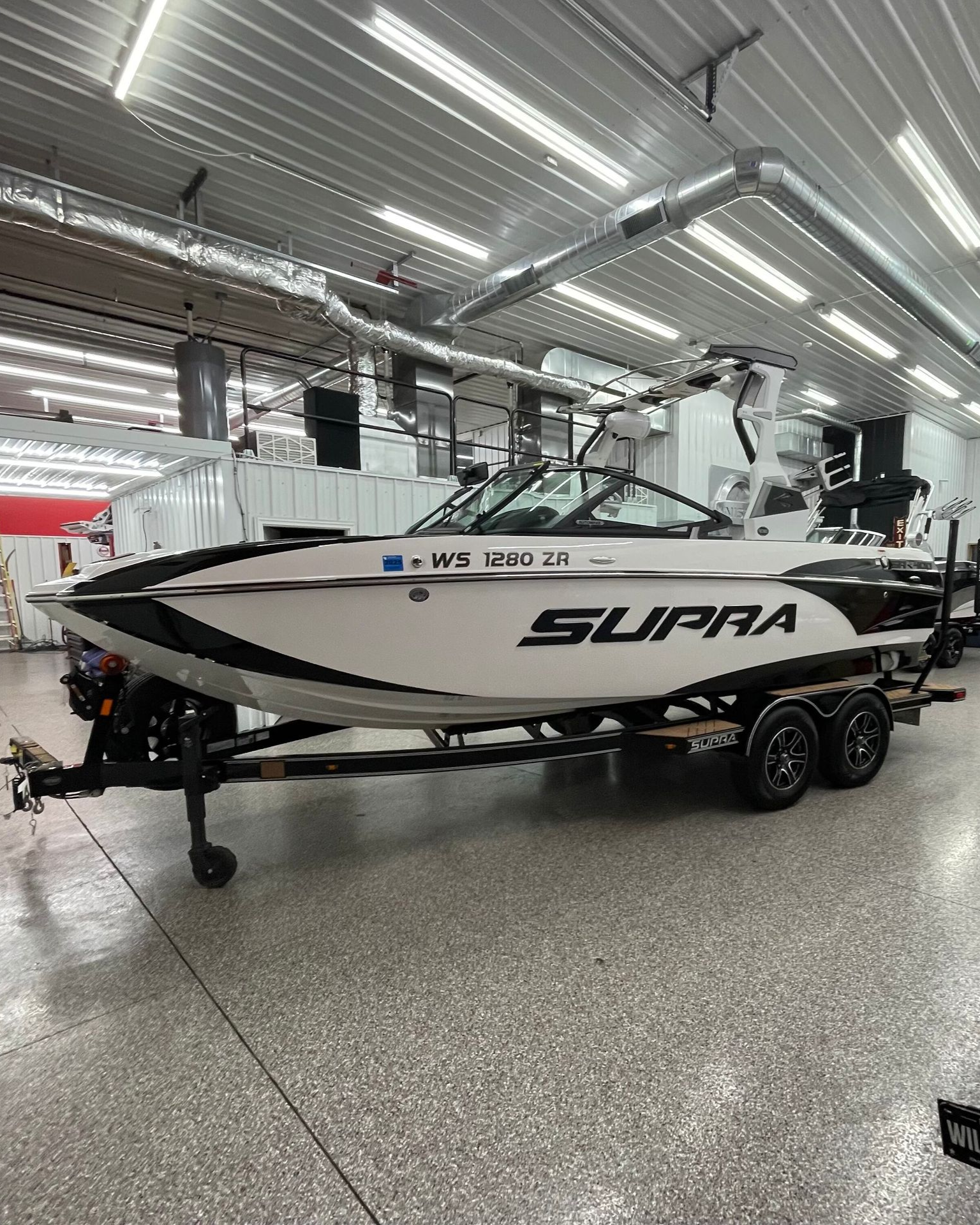 A person wearing black gloves is polishing a black car