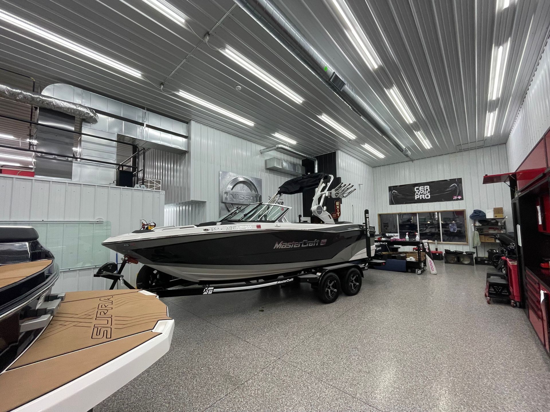 White pickup truck on a red hydraulic lift in a garage with a speckled floor and white walls.