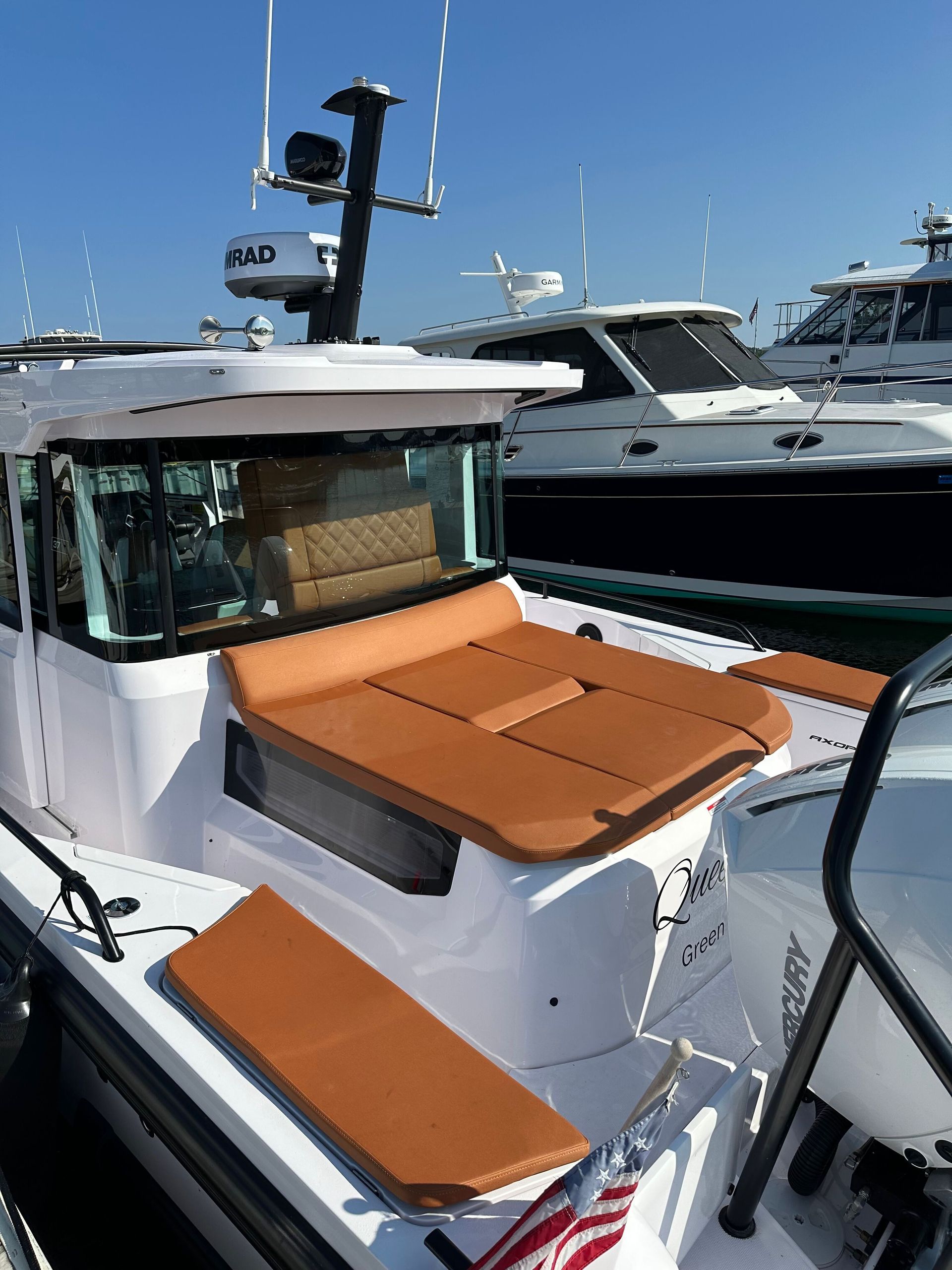 White pickup truck on a red hydraulic lift in a garage with a speckled floor and white walls.