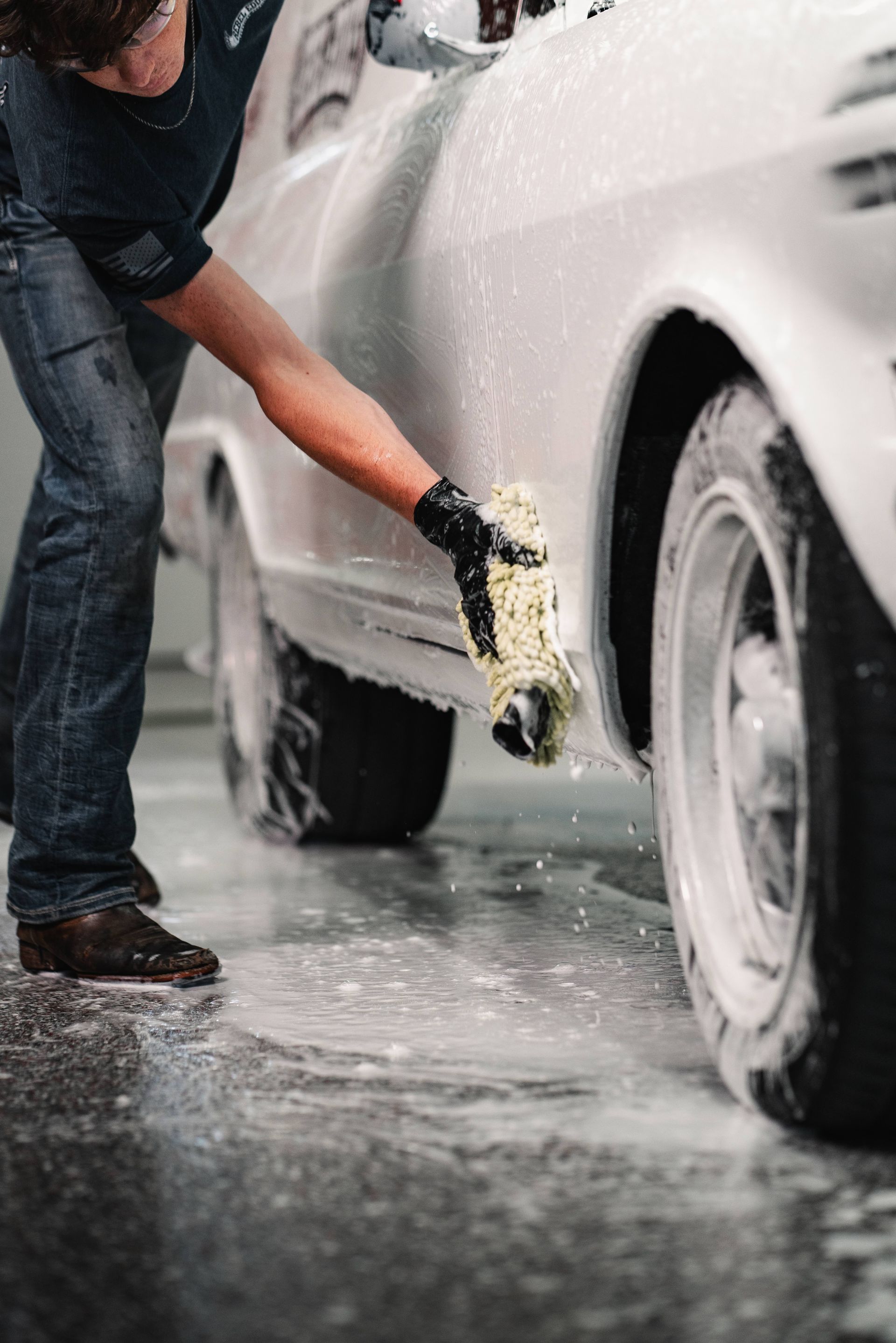 A person is washing a car wheel with foam