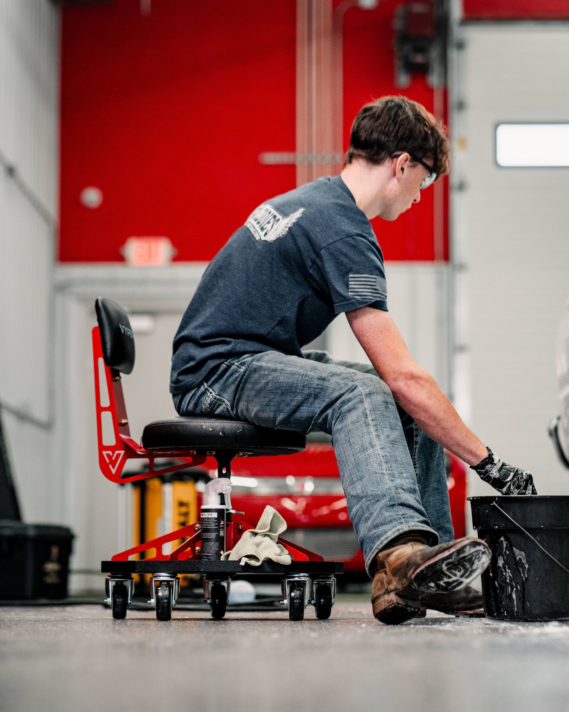 A man is cleaning the wheel of a black car with a sponge.